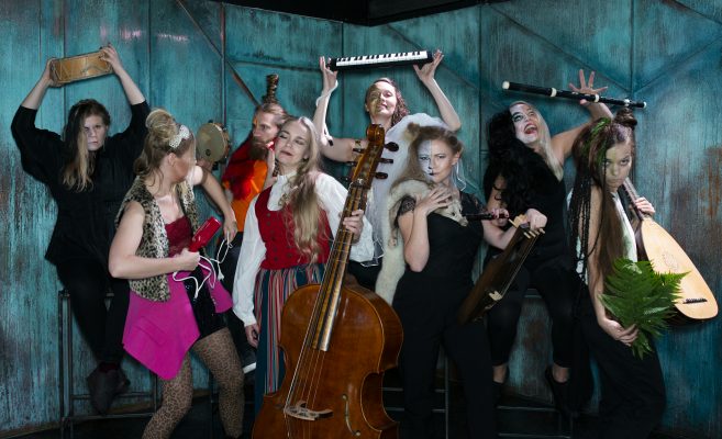 Kuvassa Pohjolan naiset monitaiteinen työryhmä soittimien ja erilaisten rooliasujen kanssa.
