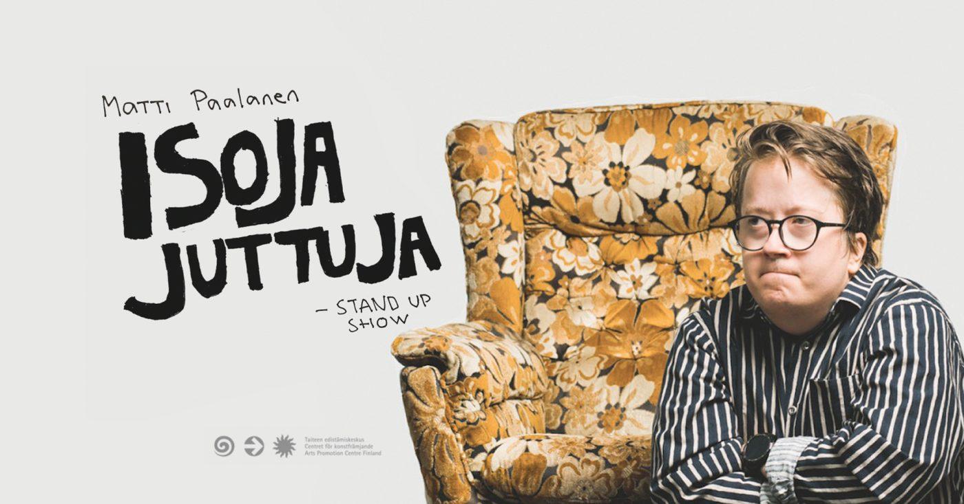 Kuvassa stand up -koomikko Matti Paalanen, taustalla kukallinen ruskeansävyinen nojatuoli sekä vasemmalla teksti Isoja juttuja -stand up show.