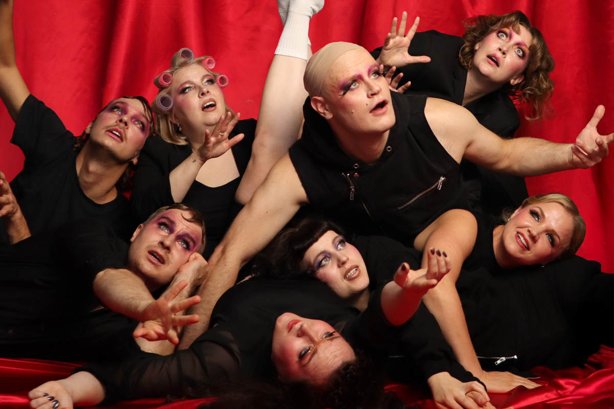 Kuvassa Musiikkiteatteri NYT:n näyttelijät punaista taustaa vasten.